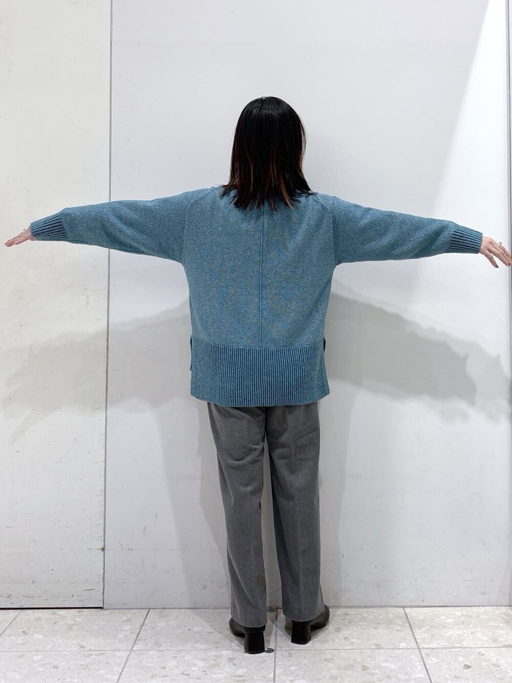 ブルー系のニット/セーター、グレー系のその他パンツ、ブラック系のトートバッグを着用したレディースの冬コーディネートの4枚目の写真