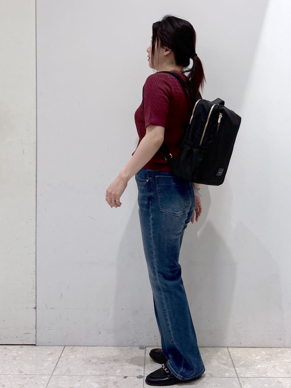 レッド系のニット/セーター、ブルー系のデニムパンツ、ブラック系のバックパック/リュックを着用したレディースの秋コーディネートの3枚目の写真