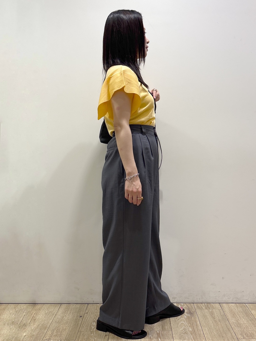 イエロー系のニット/セーター、グレー系のその他パンツ、ブラック系のショルダーバッグを着用したレディースの夏コーディネートの2枚目の写真