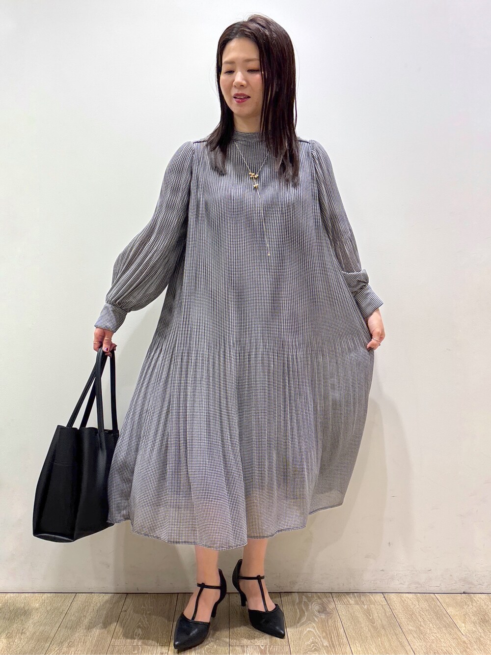 ブラック系のワンピース、ブラック系のトートバッグ、ブラック系のパンプスを着用したレディースの秋コーディネートの5枚目の写真
