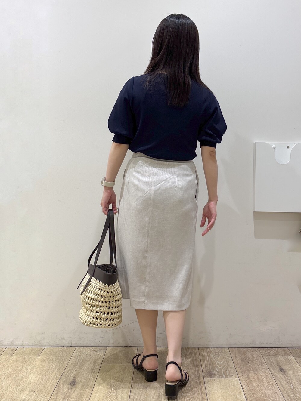 ブルー系のニット/セーター、ベージュ系のスカート、ブラウン系のトートバッグを着用したレディースの夏コーディネートの3枚目の写真