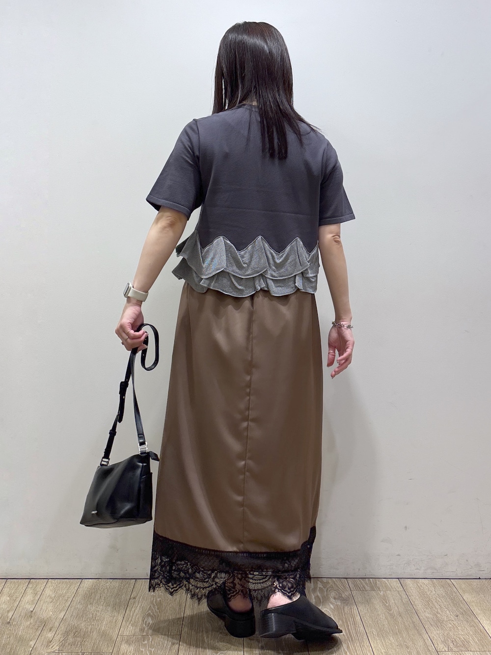 グレー系のニット/セーター、ブラウン系のスカート、ブラック系のショルダーバッグを着用したレディースの夏コーディネートの3枚目の写真