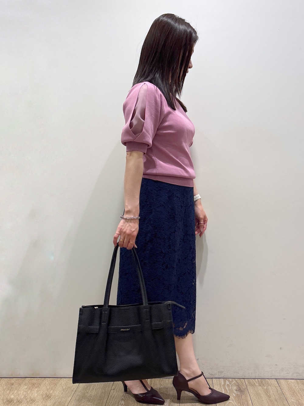 ピンク系のニット/セーター、ブラック系のトートバッグ、レッド系のパンプスを着用したレディースの夏コーディネートの2枚目の写真