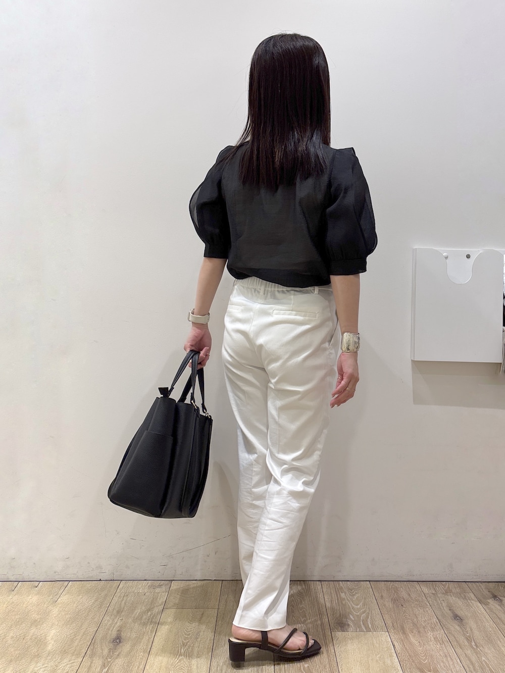 ブラック系のトートバッグ、ブラウン系のサンダル、ホワイト系のその他パンツを着用したレディースの春コーディネートの6枚目の写真