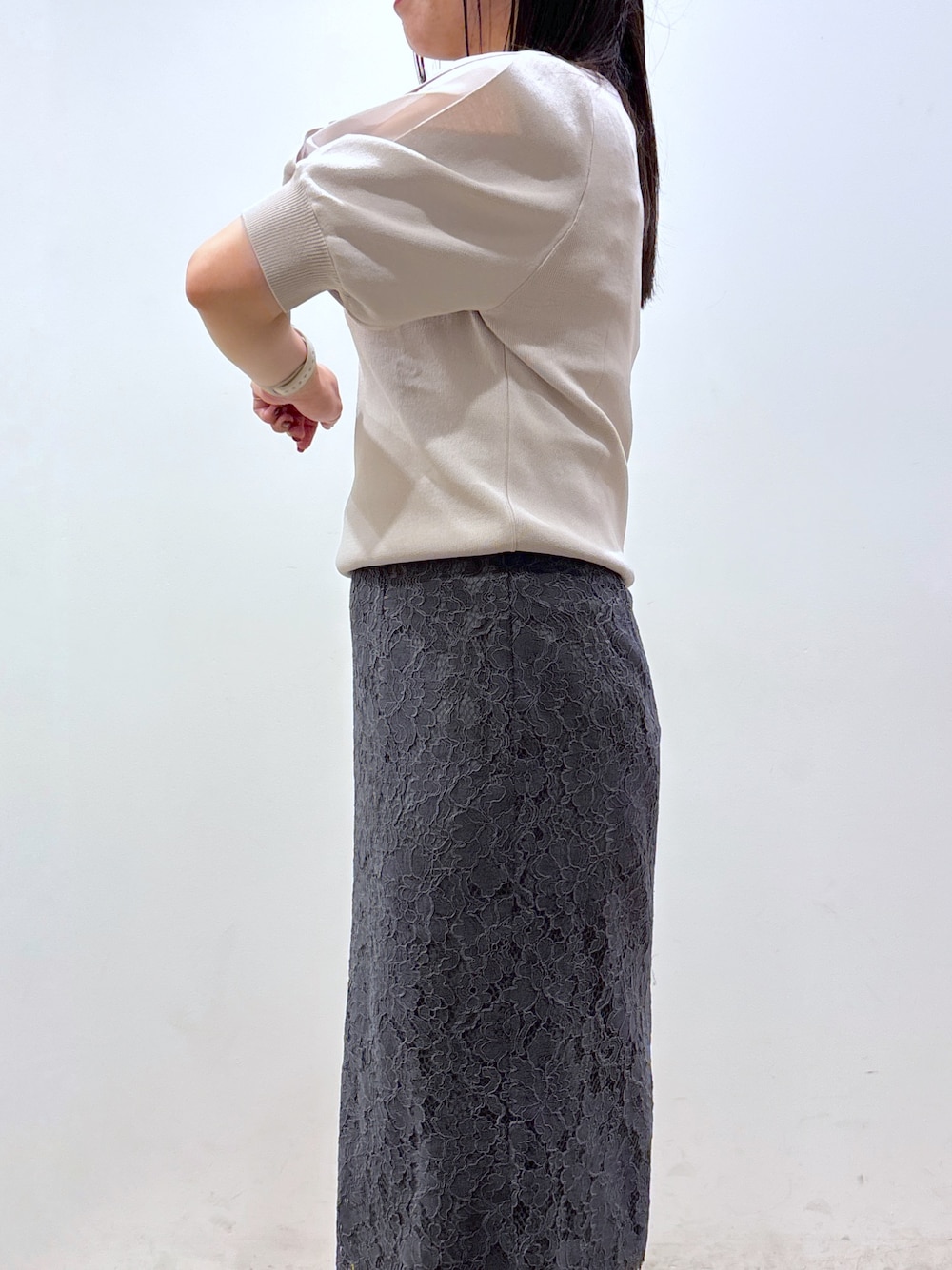 ベージュ系のニット/セーター、グレー系のスカート、ブラック系のトートバッグを着用したレディースの夏コーディネートの9枚目の写真