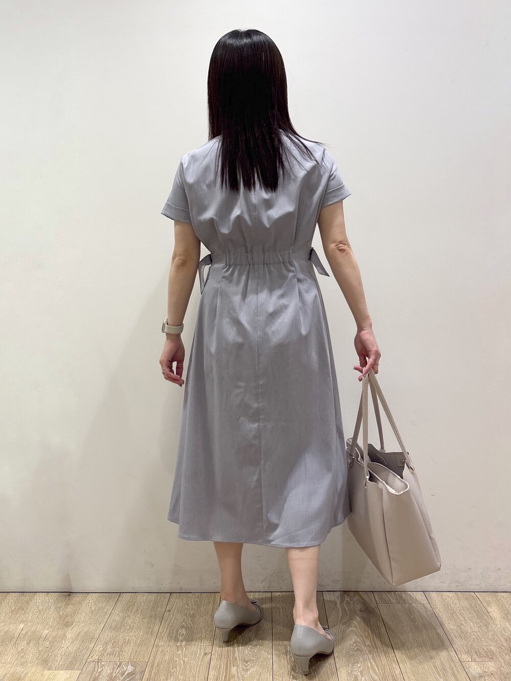 グレー系のワンピース、グレー系のトートバッグ、グレー系のパンプスを着用したレディースの夏コーディネートの3枚目の写真