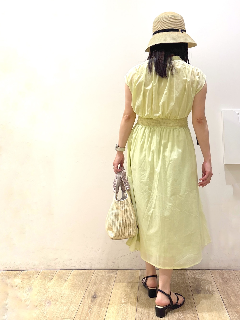 イエロー系のワンピース、ベージュ系のトートバッグ、ブラック系のサンダルを着用したレディースの夏コーディネートの3枚目の写真