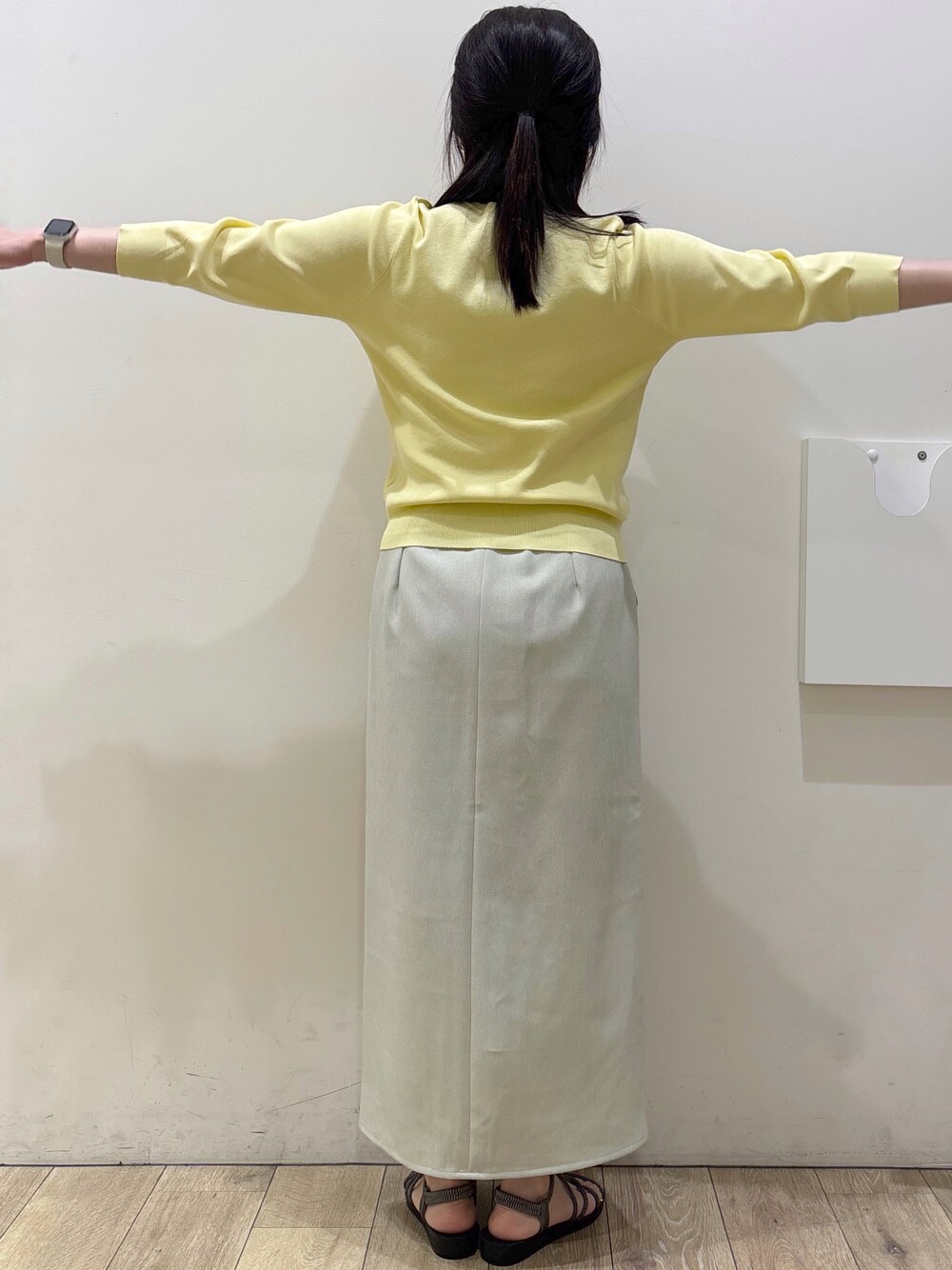 イエロー系のニット/セーター、ベージュ系のスカート、ホワイト系のトートバッグを着用したレディースの春コーディネートの8枚目の写真