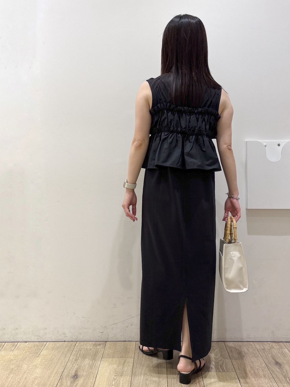 ホワイト系のトートバッグ、ブラック系のサンダルを着用したレディースの夏コーディネートの3枚目の写真