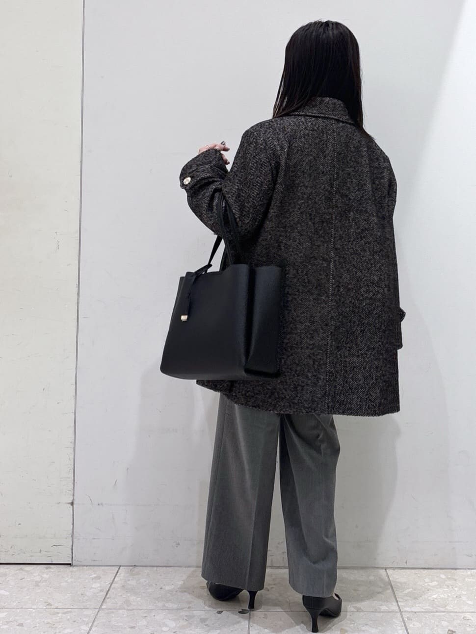 ブラック系のステンカラーコート、ブルー系のニット/セーター、グレー系のその他パンツを着用したレディースの冬コーディネートの3枚目の写真