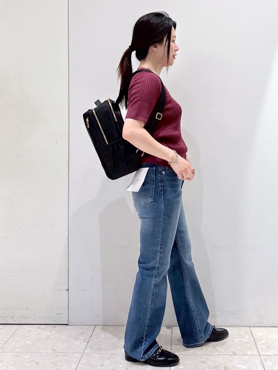 レッド系のニット/セーター、ブルー系のデニムパンツ、ブラック系のバックパック/リュックを着用したレディースの秋コーディネートの2枚目の写真