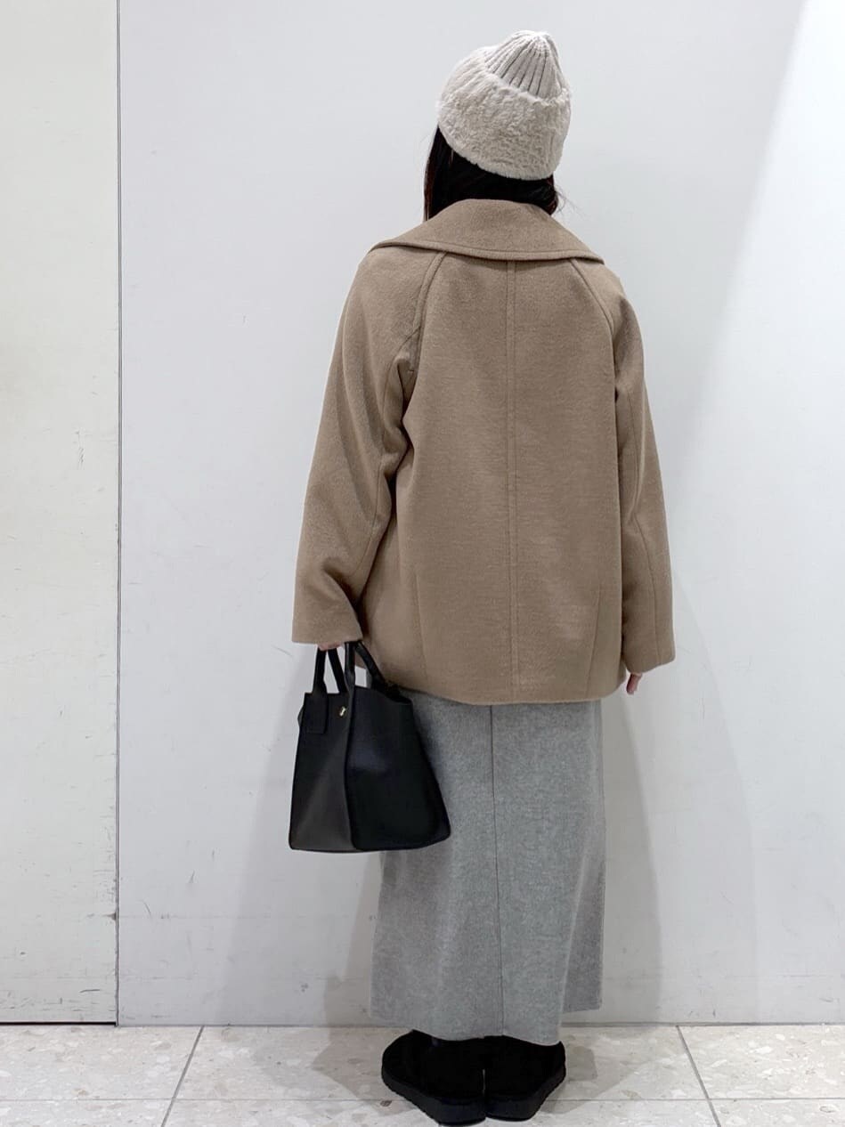 ベージュ系のピーコート、レッド系のカーディガン/ボレロ、グレー系のスカートを着用したレディースの冬コーディネートの4枚目の写真