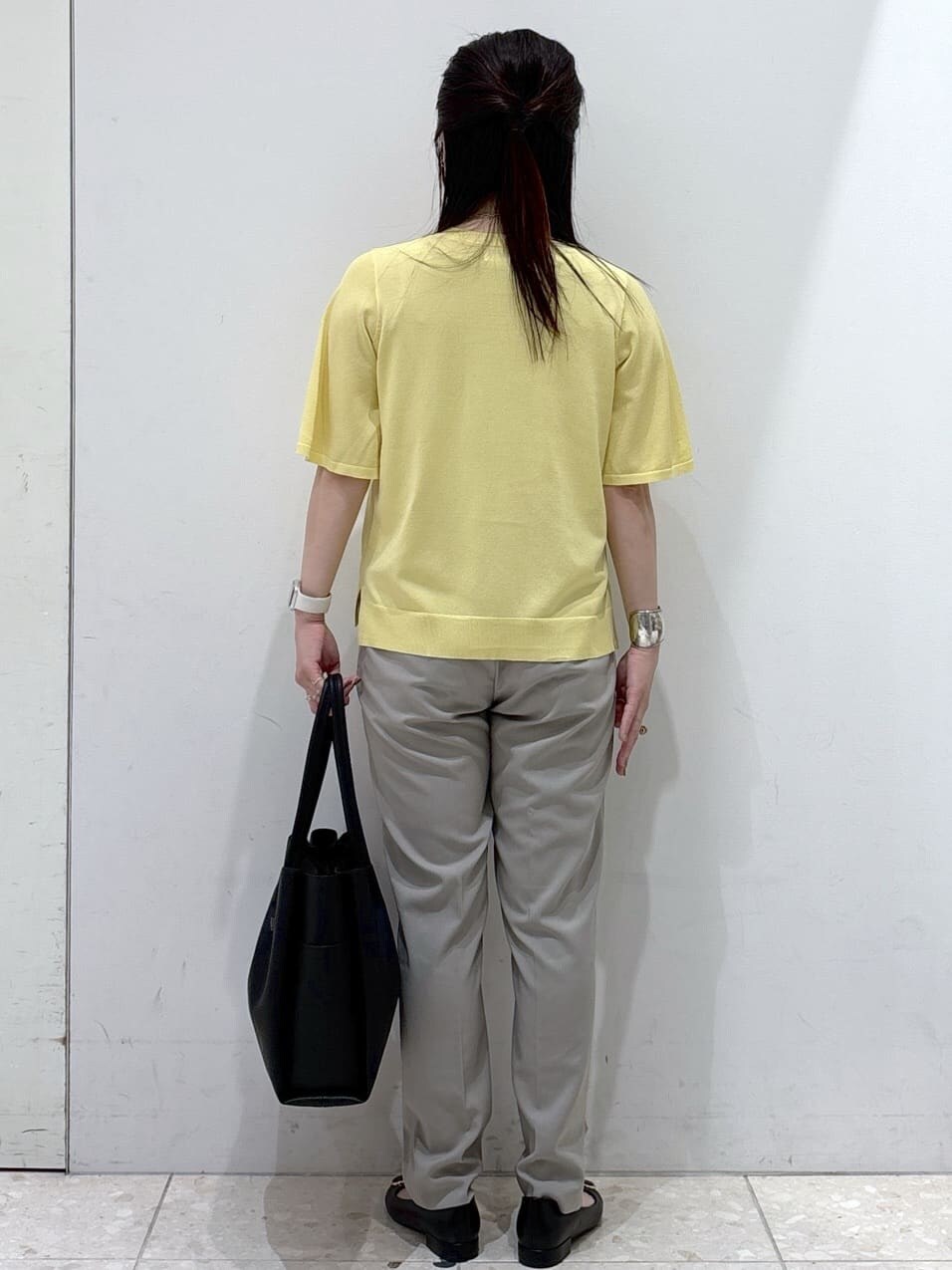イエロー系のニット/セーター、ブラウン系のその他パンツ、ブラック系のトートバッグを着用したレディースの夏コーディネートの3枚目の写真