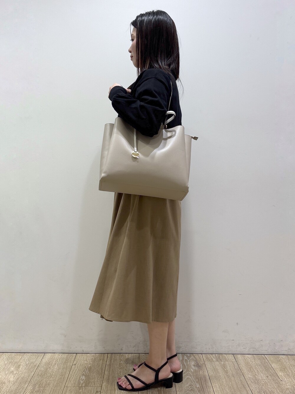 イエロー系のワンピース、ベージュ系のトートバッグ、ブラック系のサンダルを着用したレディースの夏コーディネートの2枚目の写真
