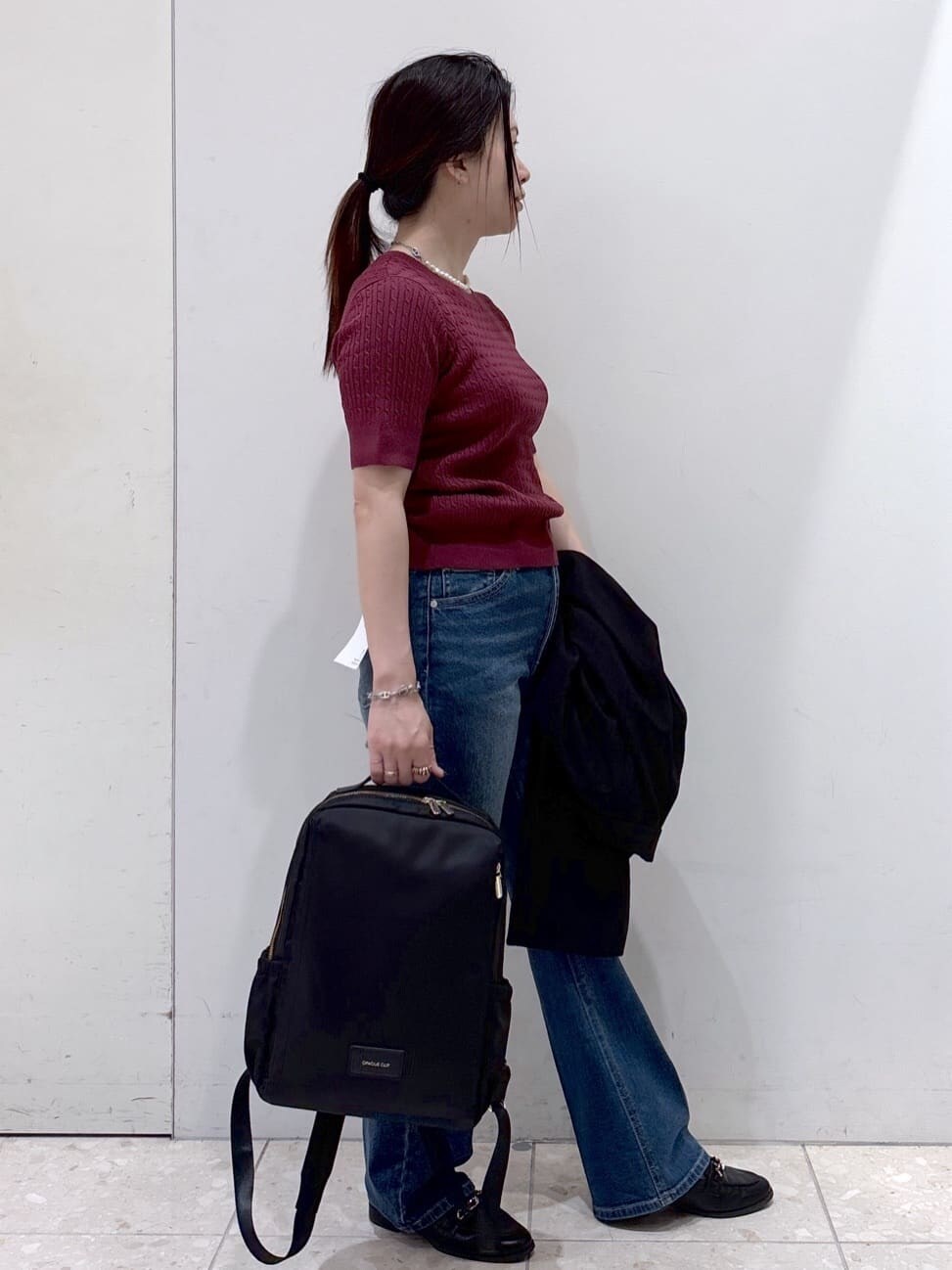レッド系のニット/セーター、ブルー系のデニムパンツ、ブラック系のバックパック/リュックを着用したレディースの秋コーディネートの5枚目の写真