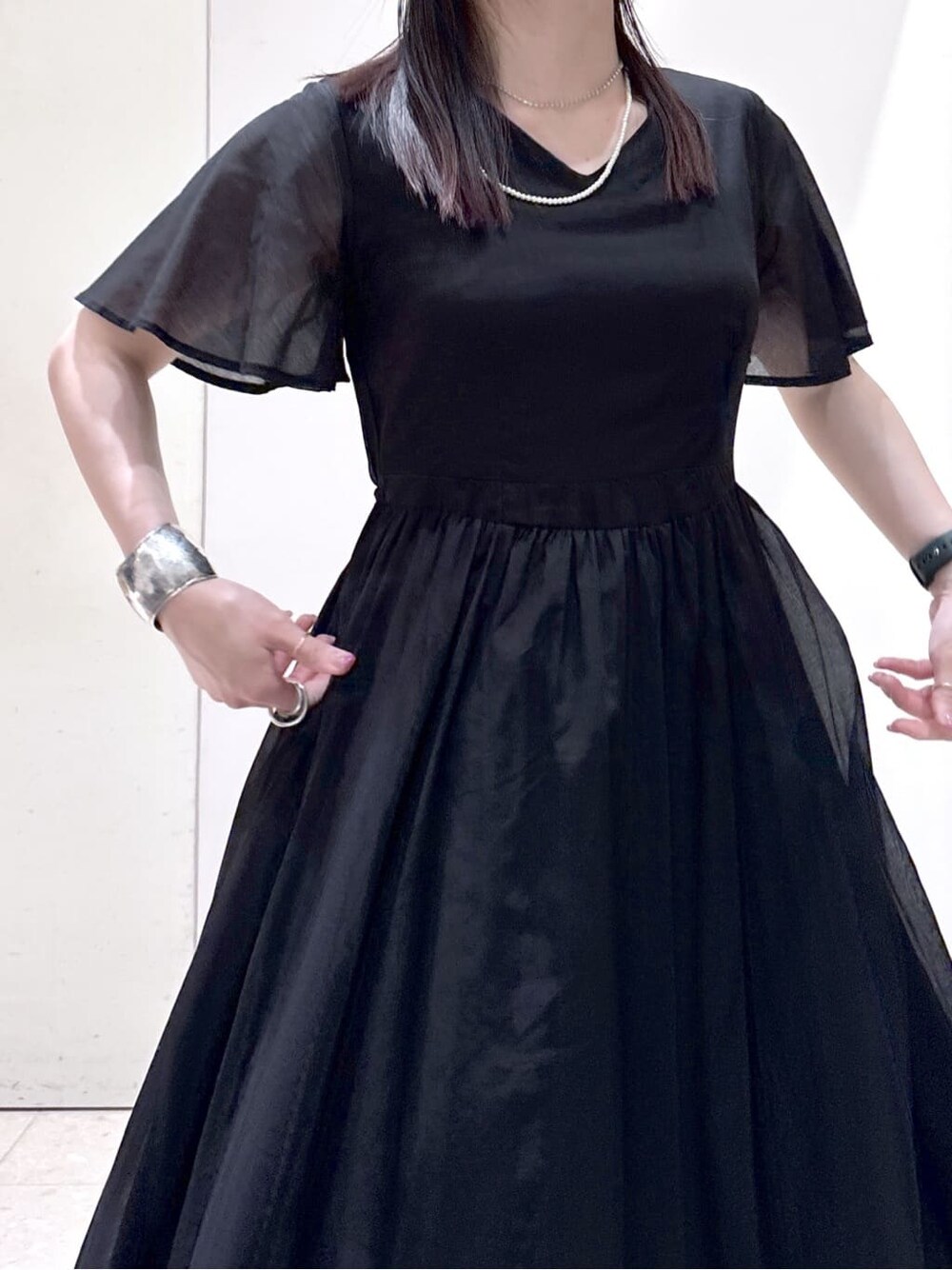 ブラック系のワンピース、ブラック系のトートバッグ、ブラック系のパンプスを着用したレディースの夏コーディネートの5枚目の写真