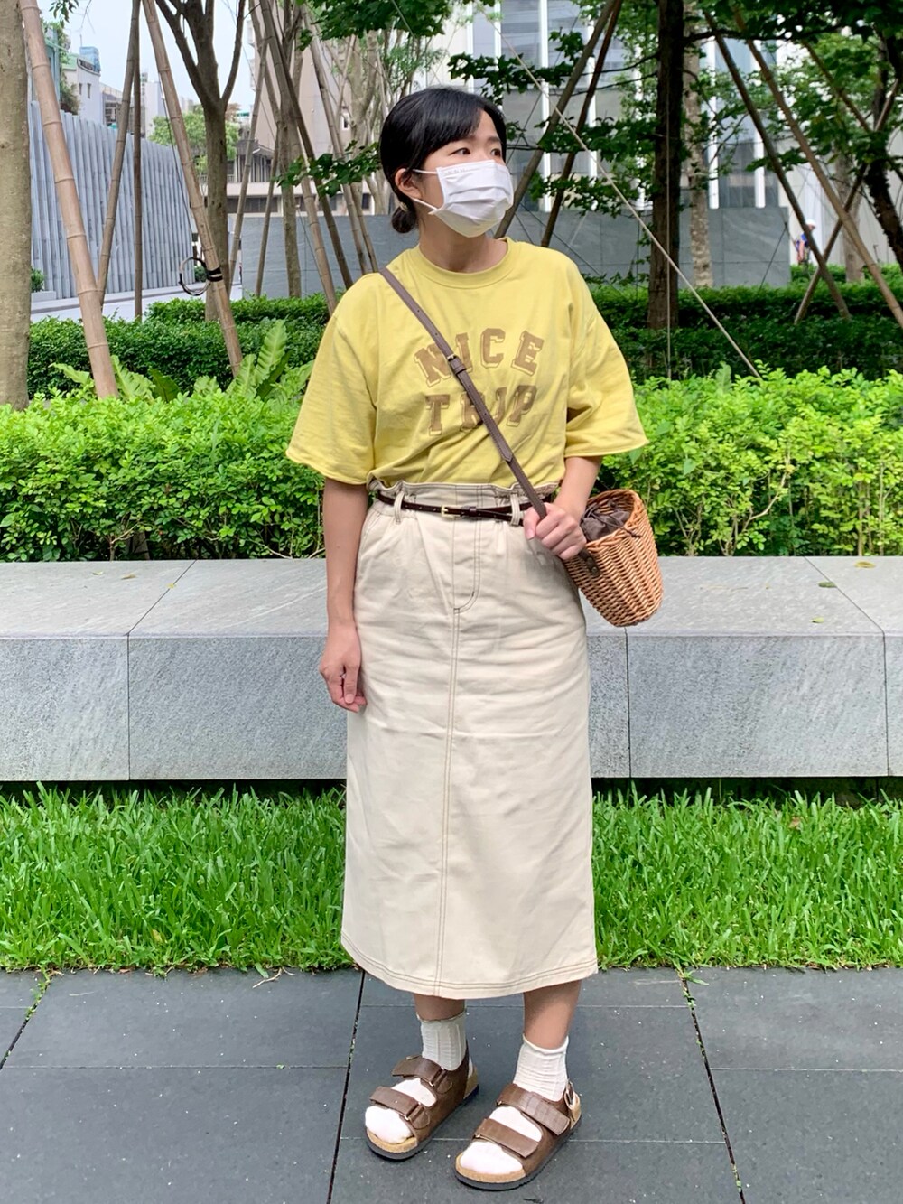 イエロー系のTシャツ/カットソー、ブラウン系のハンドバッグ、ホワイト系のスカートを着用したレディースの春コーディネートの3枚目の写真