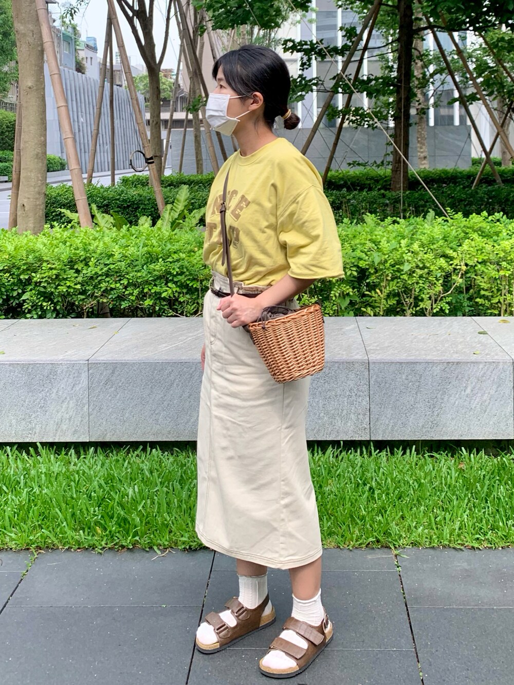 イエロー系のTシャツ/カットソー、ブラウン系のハンドバッグ、ホワイト系のスカートを着用したレディースの春コーディネートの2枚目の写真