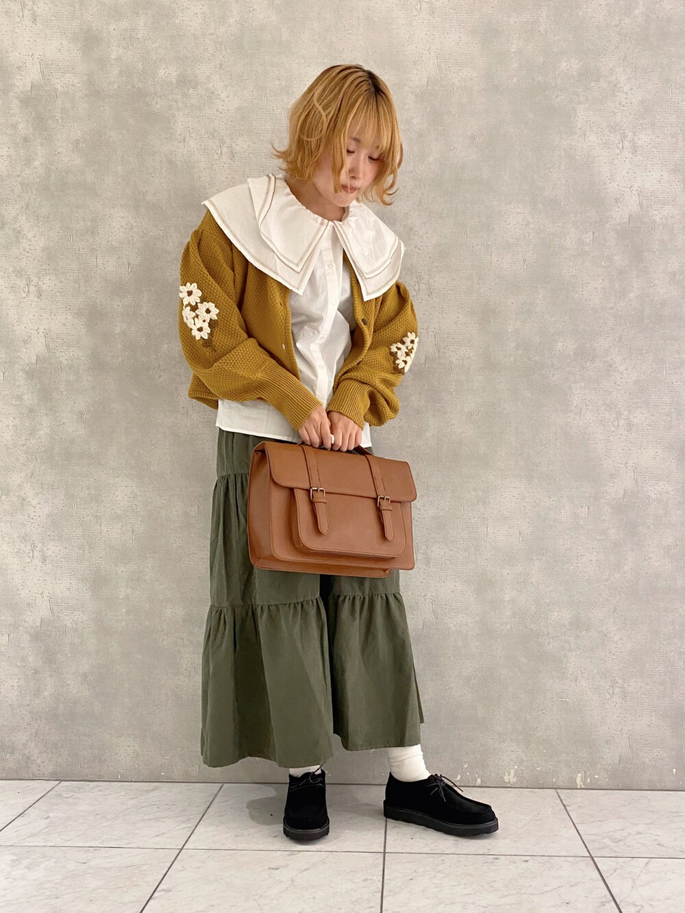 イエロー系のカーディガン/ボレロ、イエロー系のハンドバッグ、ブラック系のその他シューズを着用したレディースの秋コーディネートの2枚目の写真