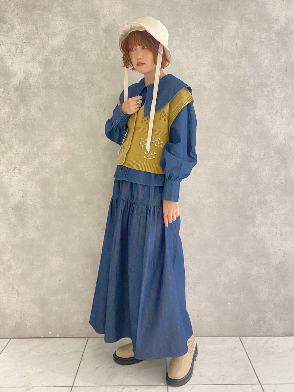 ブルー系のスカート、ブルー系のシャツ/ブラウス、イエロー系のベストを着用したレディースの秋コーディネートの2枚目の写真