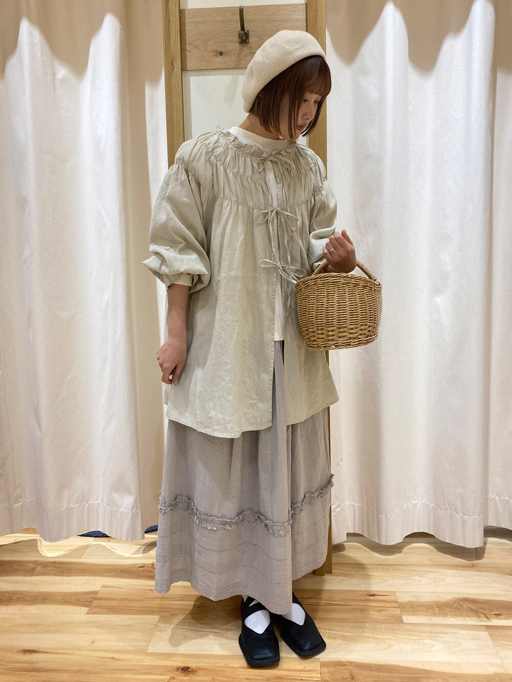 グレー系のスカート、ホワイト系のTシャツ/カットソー、ベージュ系のトップスを着用したレディースの春コーディネートの3枚目の写真