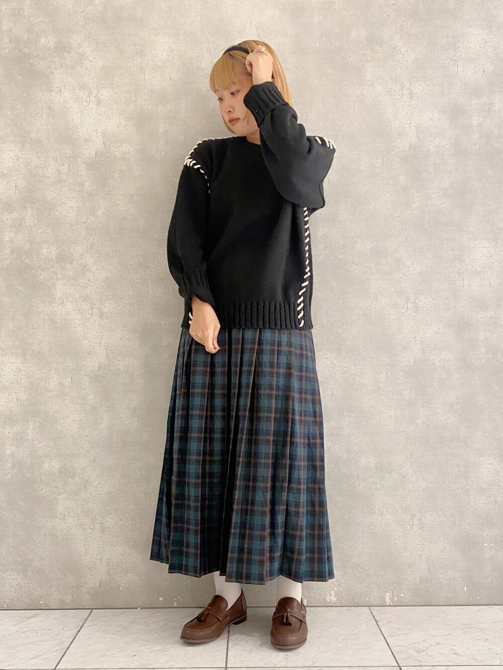 ブラック系のニット/セーター、グリーン系のスカート、ブラウン系のローファーを着用したレディースの秋コーディネートの2枚目の写真