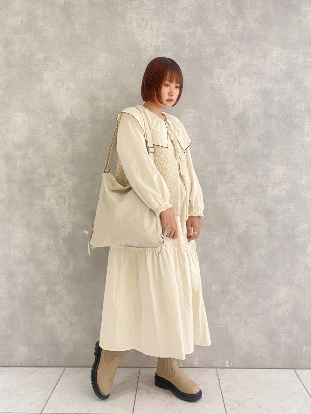 ホワイト系のベスト、ホワイト系のワンピース、ベージュ系のブーツを着用したレディースの秋コーディネートの2枚目の写真