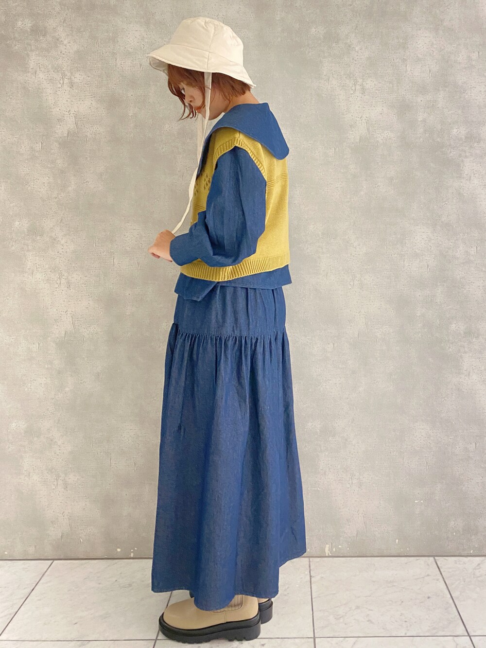 ブルー系のスカート、ブルー系のシャツ/ブラウス、イエロー系のベストを着用したレディースの秋コーディネートの3枚目の写真