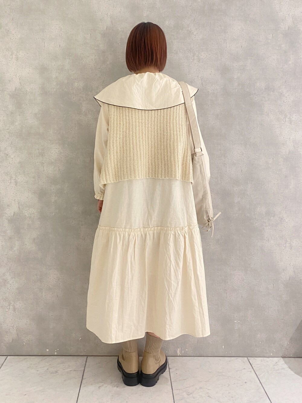 ホワイト系のベスト、ホワイト系のワンピース、ベージュ系のブーツを着用したレディースの秋コーディネートの3枚目の写真