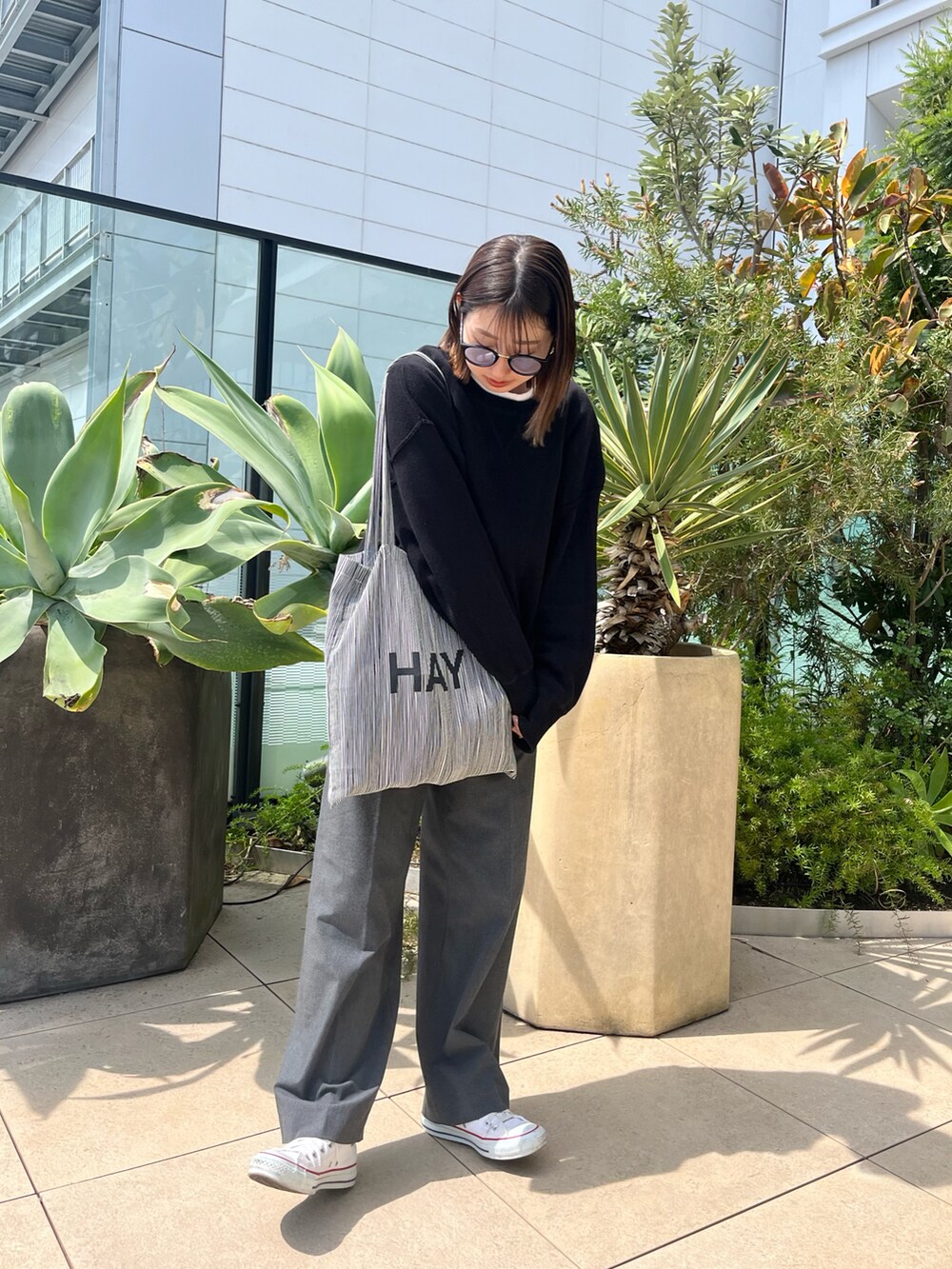 ブラック系のニット/セーター、ホワイト系のTシャツ/カットソー、グレー系のスラックスを着用したレディースの春コーディネートの3枚目の写真