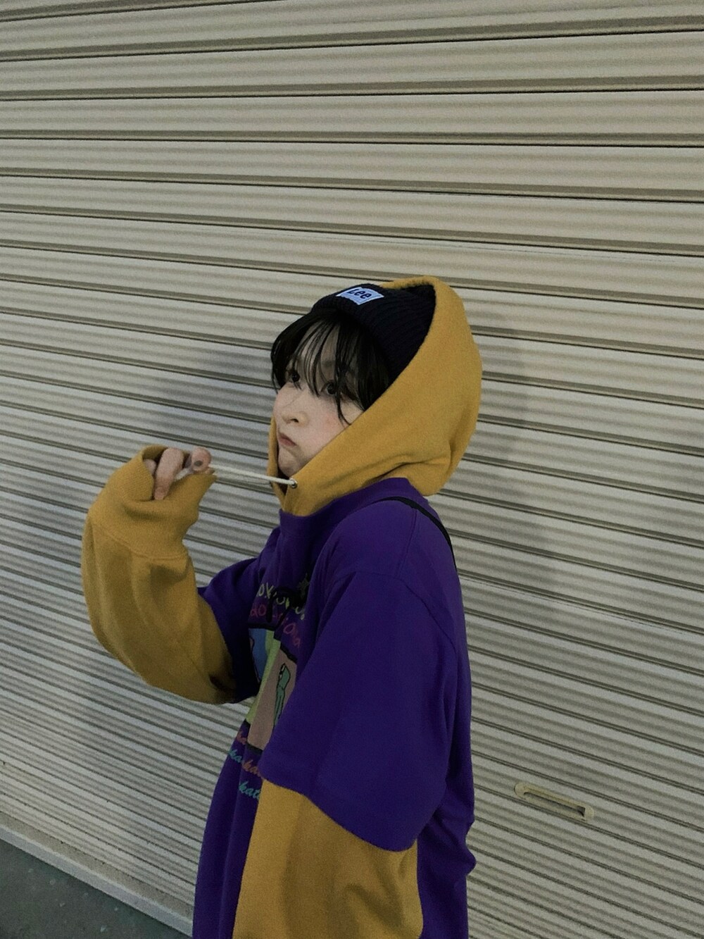 イエロー系のパーカー、パープル系のTシャツ/カットソー、ホワイト系のデニムパンツを着用したレディースの冬コーディネートの2枚目の写真