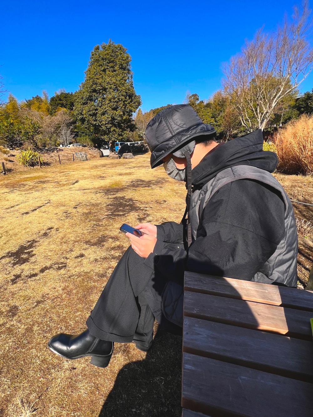 グレー系のダウンベスト、ブラック系のその他アウター、ブラック系のスラックスを着用したメンズの冬コーディネートの2枚目の写真