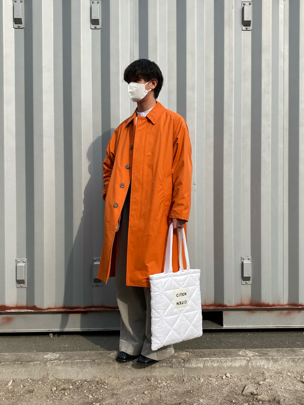 オレンジ系のステンカラーコート、ホワイト系のシャツ/ブラウス、グレー系のデニムパンツを着用したメンズの春コーディネートの2枚目の写真
