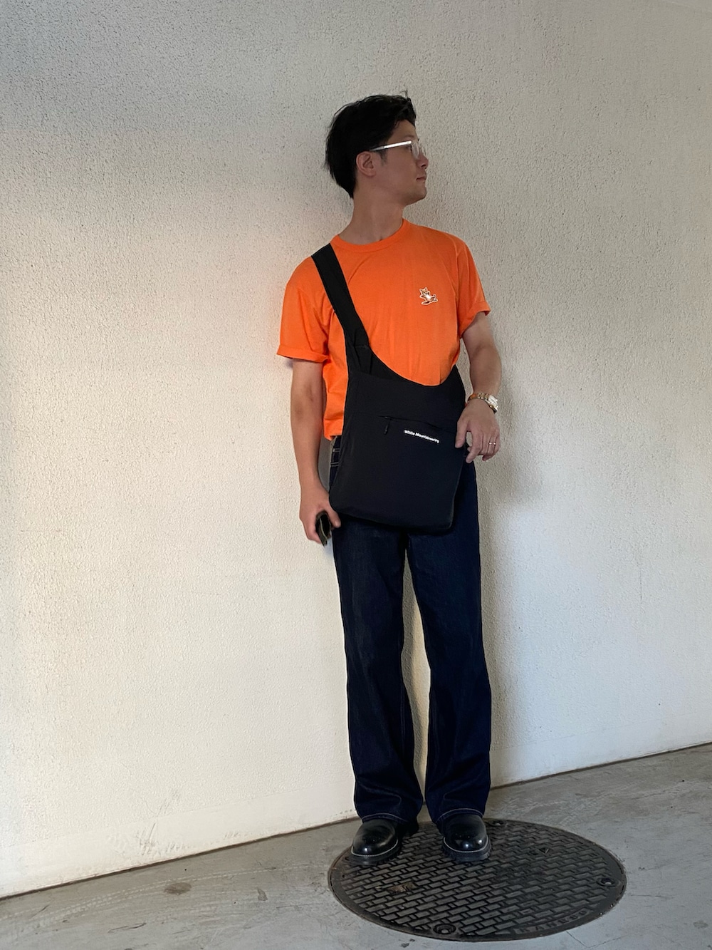 オレンジ系のTシャツ/カットソー、ブラック系のショルダーバッグ、ブラック系のその他シューズを着用したメンズの夏コーディネートの2枚目の写真