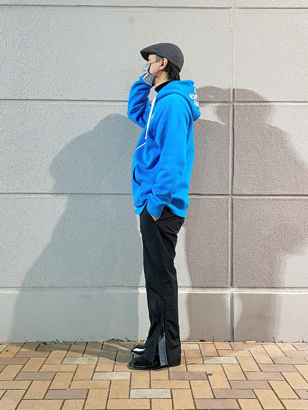 ブルー系のパーカー、ブラック系のブーツ、グレー系のハンチング/ベレー帽を着用したメンズの春コーディネートの2枚目の写真