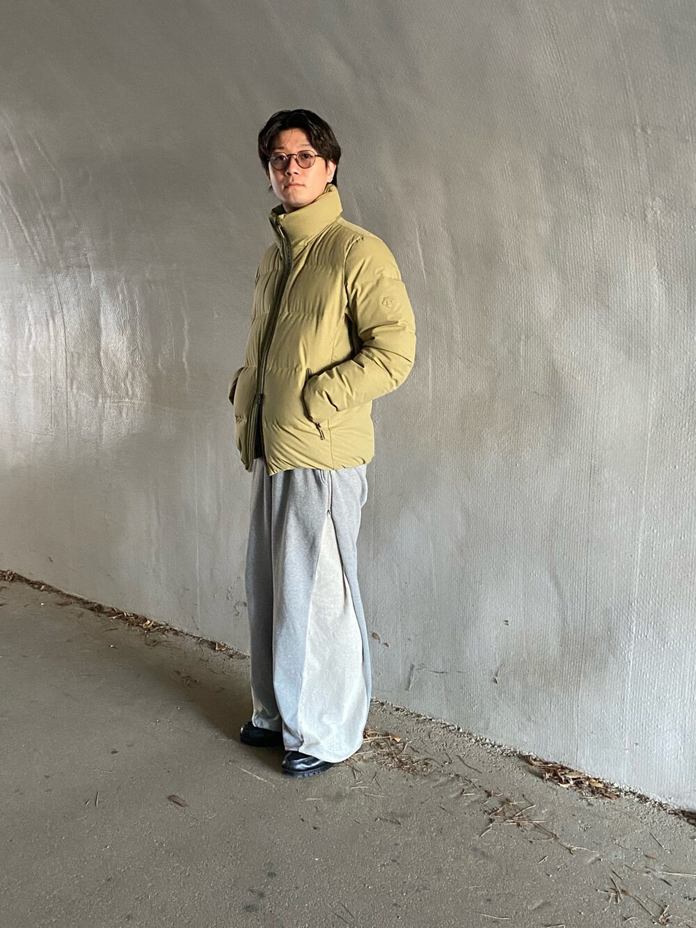 グレー系のスウェットパンツ、ブラック系のドレスシューズ、グリーン系のダウンジャケット/コートを着用したメンズの冬コーディネートの2枚目の写真