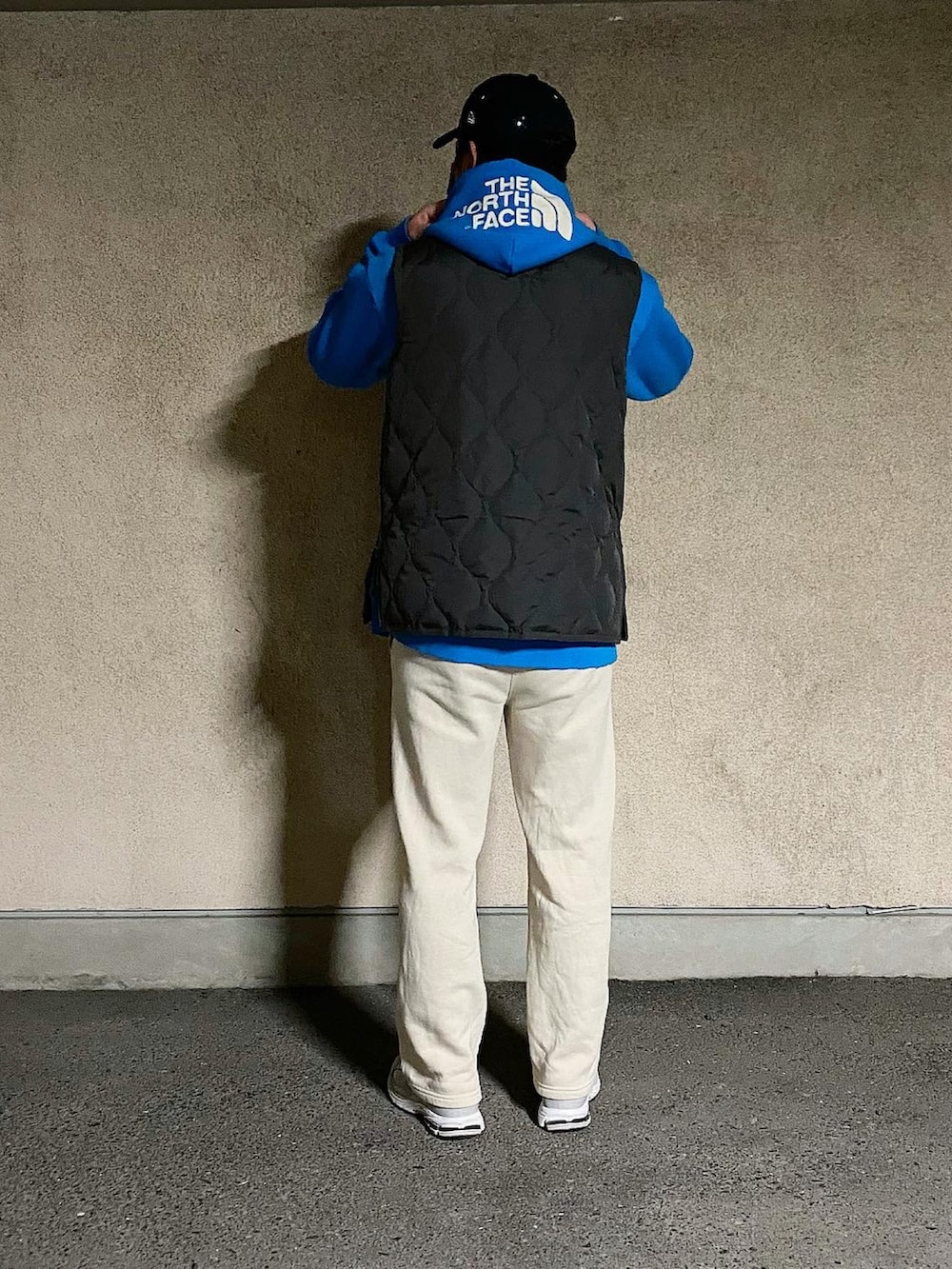 グレー系のダウンベスト、ブルー系のパーカー、グレー系のスニーカーを着用したメンズの冬コーディネートの2枚目の写真