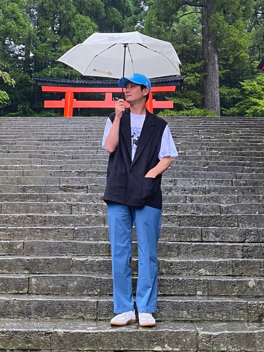 ホワイト系のTシャツ/カットソー、ブラック系のベスト、ブルー系のスラックスを着用したメンズの春コーディネートの2枚目の写真