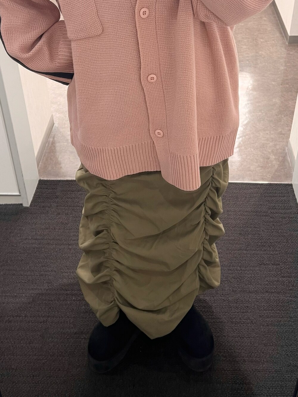 グリーン系のスカート、ピンク系のブルゾン、ブラック系のブーツを着用したレディースの冬コーディネートの3枚目の写真