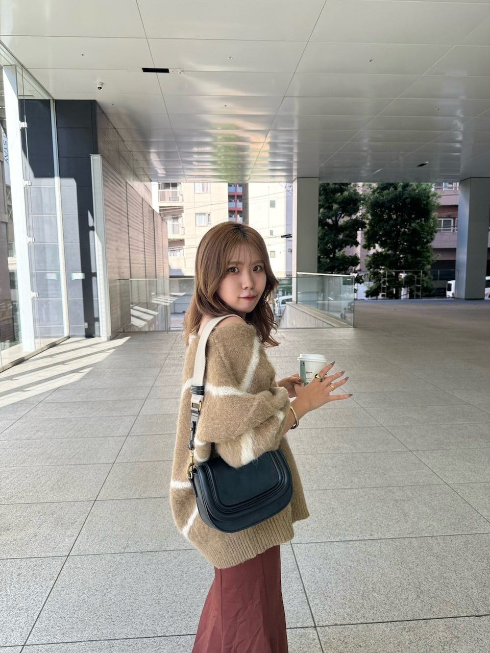 ブラウン系のスカート、ホワイト系のブーツ、ブラウン系のニット/セーターを着用したレディースの秋コーディネートの4枚目の写真