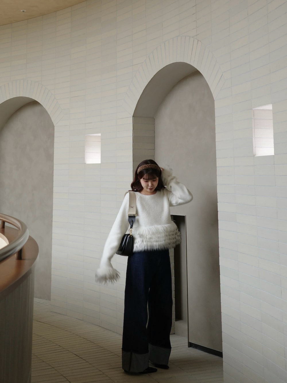 ブルー系のデニムパンツ、ホワイト系のニット/セーターを着用したレディースの冬コーディネートの2枚目の写真