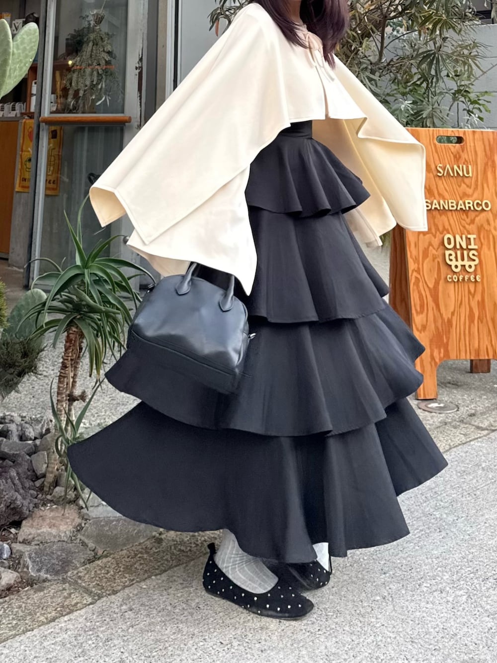 ベージュ系のトップス、ブラック系のスカート、ブラック系のパンプスを着用したレディースの春コーディネートの2枚目の写真