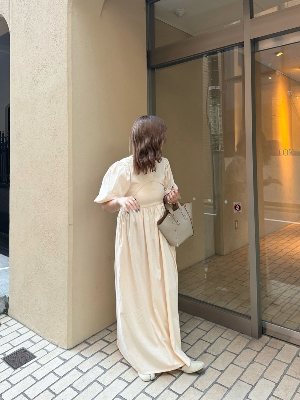 ベージュ系のハンドバッグ、ホワイト系のワンピース、ベージュ系のサンダルを着用したレディースの夏コーディネートの5枚目の写真