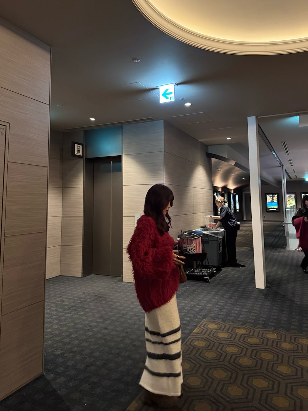 ブラウン系のボストンバッグ、レッド系のニット/セーター、ホワイト系のスカートを着用したレディースの冬コーディネートの2枚目の写真