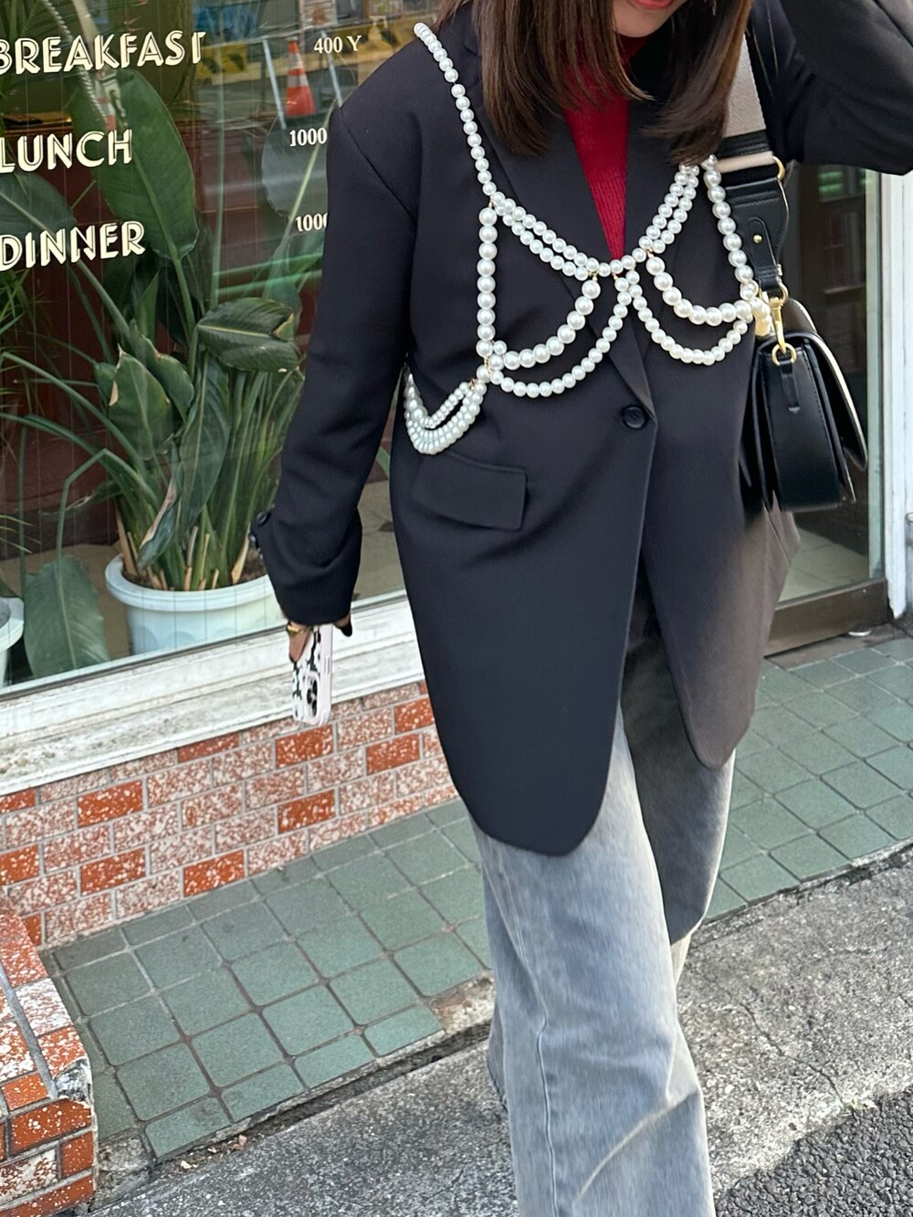 ブラック系のショルダーバッグ、ブラック系のブーツ、ブラック系のデニムパンツを着用したレディースの冬コーディネートの2枚目の写真