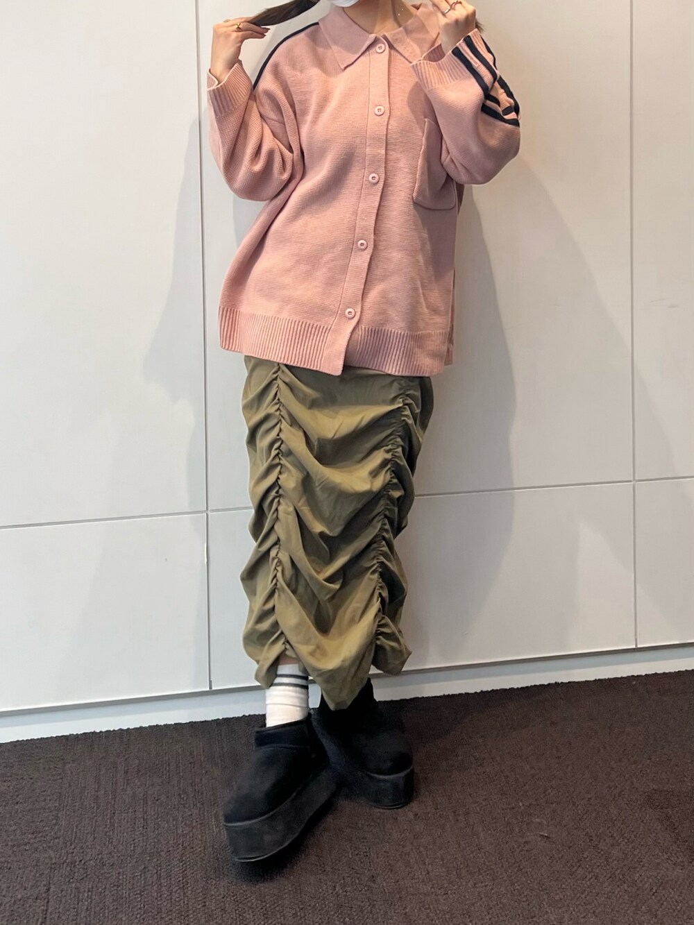 グリーン系のスカート、ピンク系のブルゾン、ブラック系のブーツを着用したレディースの冬コーディネートの2枚目の写真