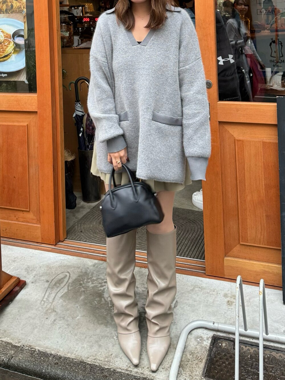 ベージュ系のブーツ、ブラック系のボストンバッグ、グレー系のニット/セーターを着用したレディースの秋コーディネートの2枚目の写真