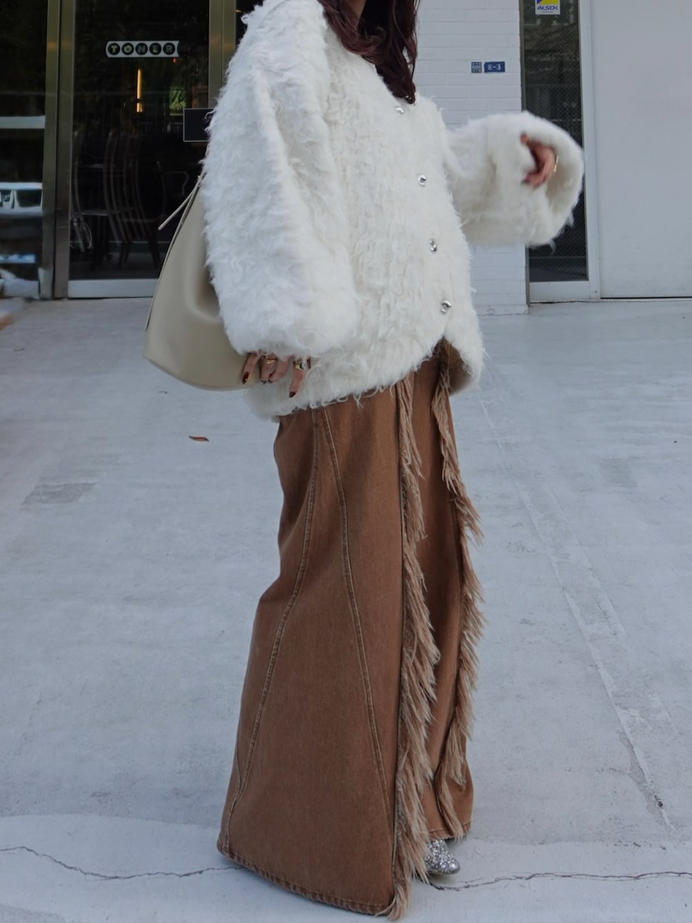 ホワイト系のニット/セーター、ブラウン系のデニムパンツ、シルバー系のローファーを着用したレディースの秋コーディネートの3枚目の写真