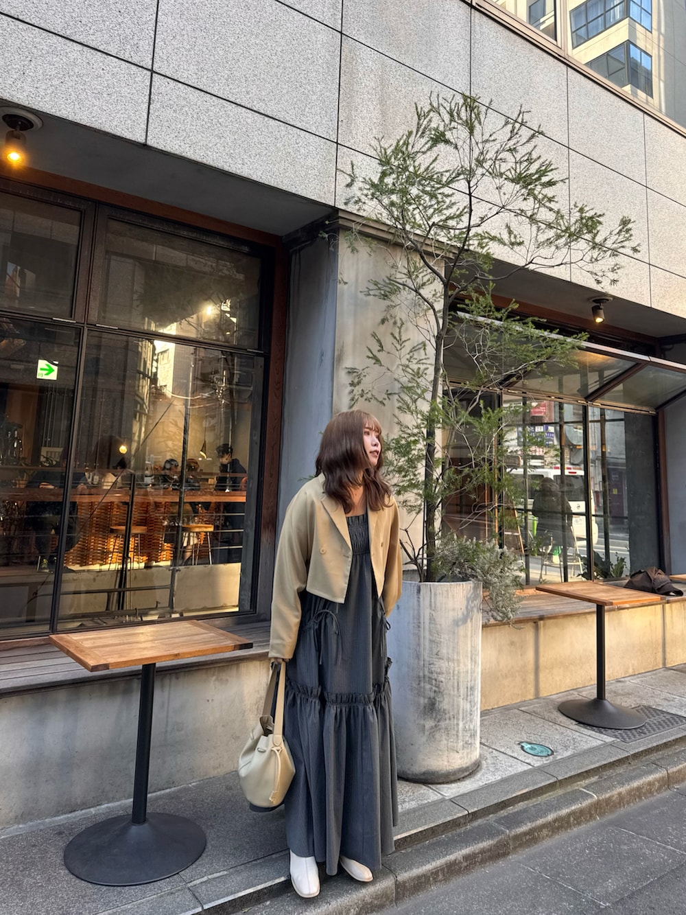 ベージュ系のテーラードジャケット、ブラック系のワンピース、ベージュ系のショルダーバッグを着用したレディースの春コーディネートの4枚目の写真