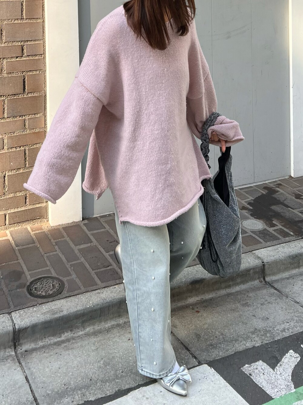 シルバー系のトートバッグ、シルバー系のパンプス、ブルー系のデニムパンツを着用したレディースの冬コーディネートの3枚目の写真